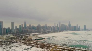 Chicago ufuk çizgisindeki karlı marina manzarası. Donmuş liman, arka planda yüksek binalar. Karda buzlu yeşil su birikintileriyle dolu boş rıhtımlar. Yüksek kalite 4k görüntü