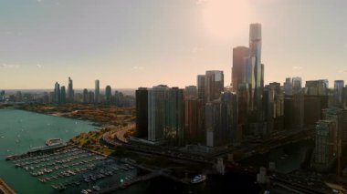 Hava Aracı, gün batımında gökdelenlerin arkasında parlayan altın güneş ışığıyla Chicago gökyüzü manzaralı. Michigan Gölü manzaralı. Yüksek kalite 4k görüntü