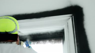 Boyacı pencereyi sprey makineyle siyah renge boyuyor. Kullanışlı resim. Geniş açı. Yüksek kalite 4k görüntü