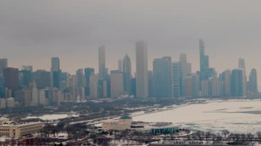 Karlı bir Chicago şehrinin gökyüzü manzarası. Donmuş liman, arka planda yüksek binalar. Karda buzlu yeşil su birikintileri. Yüksek kalite 4k görüntü