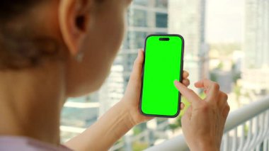 Binaların arka planında yeşil ekran modeli olan akıllı telefon kullanan kadın. - Evet. Yüksek kalite 4k görüntü