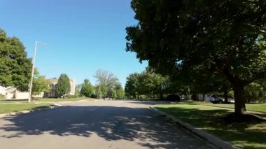 Hareket halindeki bir arabadan çekilen geniş bir bakış açısı, parlak ve güneşli bir sabahta ABD 'deki bir parkın yakınındaki yerleşim yerinin görüntüsünü alıyor. Yüksek kalite 4k görüntü