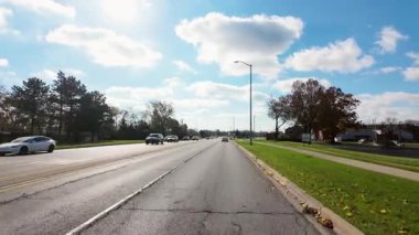 Dışarıdaki POV, güneşli bir günde sonbahar ağaçlarıyla küçük kasaba sokaklarında hareket eden arabadan ateş ediyor. Sıcak renkler ve bulutlu gökyüzü mahallelerin güzel bir resmini oluşturur. - Evet. Yüksek kalite 4k görüntü