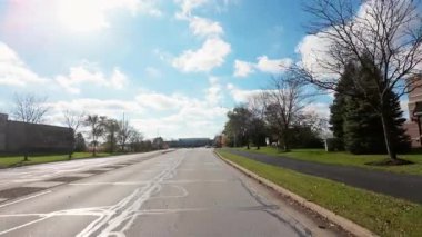 Dışarıdaki polis, güneşli bir günde sonbahar ağaçlarıyla dolu sokaklar boyunca hareket eden arabadan ateş ediyor. Sıcak renkler ve bulutlu gökyüzü mahallelerin güzel bir resmini oluşturur. - Evet. Yüksek kalite 4k görüntü