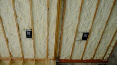 Fiberglas yalıtım malzemesi evin bodrumundaki ahşap duvarlar arasına ya da inşaat alanına monte edilmiş. Manzarayı kapat. Yüksek kalite 4k görüntü