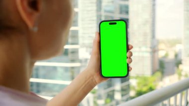 Binaların arka planında Yeşil Ekran Mockup 'lı Akıllı Telefon' u izleyen bir kadın. - Evet. Yüksek kalite 4k görüntü