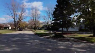 POV, sonbahar ağaçlarıyla dolu bir cadde boyunca hareket eden ve yaya geçidini işaret eden arabadan çekilmiş. Komşuların sıcak ve güzel resimleri. Yan görüş. Yüksek kalite 4k görüntü