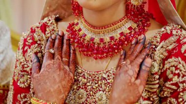 Gelin ellerini omuzlarında tutuyor. Geleneksel kızıl Hint kıyafetleri giyiyor. Hindu düğünü unsurları. Kapatın. Yüksek kalite 4k görüntü