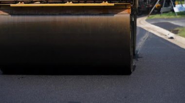 Yol silindiri, savaş halinde, yol yüzeyine asfalt bastırıyor. Ön manzara. Yüksek kalite 4k görüntü