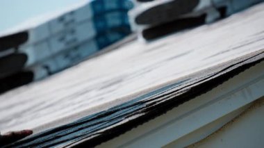 Roofer konutun çatısına kiremitleri çiviliyor. Çatı yenileme elementi. Yüksek kalite 4k görüntü