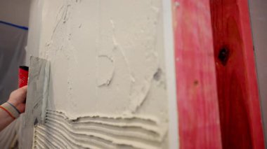 Profesyonel inşaat işçisi seramik fayansları yapıştırmak için duvara yapıştırıcı sürüyor. - Evet. Yüksek kalite 4k görüntü