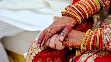 Düğün çifti birbirlerinin ellerinden tutuyorlar, geleneksel kızıl Hint kıyafetleri giyiyorlar, Hindu düğününün unsurları. Kapatın. Yüksek kalite 4k görüntü