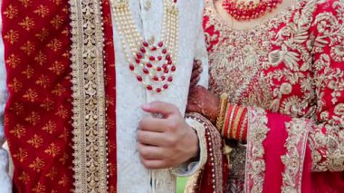 Düğün çifti el ele tutuşuyor, geleneksel kızıl Hint kıyafetleri giyiyorlar, Hindu düğünü unsurları. Kapatın. Yüksek kalite 4k görüntü