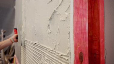 Profesyonel inşaat işçisi seramik fayansı yapıştırmak için duvara kalın bir yapıştırıcı sürüyor. - Evet. Yüksek kalite 4k görüntü