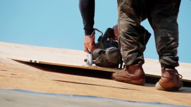 Roofer konut evindeki ahşap panelleri kesiyor. Çatı yenileme elementi. Yüksek kalite 4k görüntü