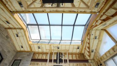 Fiberglas yalıtımı, evin çatısındaki ahşap duvar çivileri ile inşaat alanının arasına kurulmuş. Manzarayı kapat. Yüksek kalite 4k görüntü