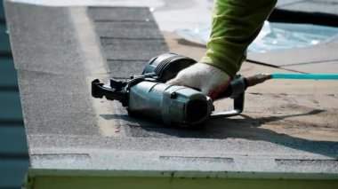 Çatıcılar yeni bir çatı kiremitini çiviliyor ve eli çatıda birkaç kez tıkırdıyor. Çatı yenileme elementi. Yüksek kalite 4k görüntü