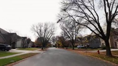 POV, parlayan sonbahar ağaçlarıyla birlikte yerleşim yeri caddesi boyunca hareket eden arabadan ateş ediyor. Sıcak renkler ve parlak mavi gökyüzü mahallelerin güzel bir resmini oluşturur. - Evet. Yüksek kalite 4k görüntü