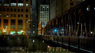 Geceleri Chicago 'da. Gece vakti Chicago şehir merkezinde nehrin karşısındaki yüksek ulaşım köprüsü. - Evet. Yüksek kalite 4k görüntü