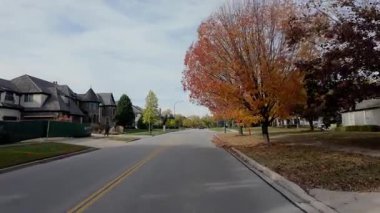 POV, parlayan sonbahar ağaçlarıyla birlikte yerleşim yeri caddesi boyunca hareket eden arabadan ateş ediyor. Sıcak sonbahar renkleri ve parlak mavi gökyüzü mahallelerin güzel bir resmini oluşturur. - Evet. Yüksek kalite 4k görüntü