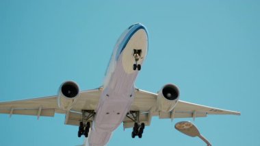 Kafasının üzerinden uçan uçak, güneşli bir günde dikenli tellerle havaalanına iniyor. Yavaş çekim. Yüksek kalite 4k görüntü