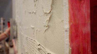 Profesyonel inşaat işçisi seramik fayansı yapıştırmak için duvara kalın bir tutkal yapıştırıyor. - Evet. Yüksek kalite 4k görüntü