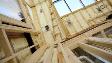Fiberglas yalıtım malzemesi evin çatısındaki ahşap duvarların arasına ya da şantiyeye monte edilmiş. Manzarayı kapat. Yüksek kalite 4k görüntü