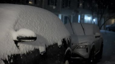 Kar fırtınası gecesinde kar ile kaplı, cam sileceklerini kaldırmış park halindeki arabaları çekiyoruz. Yüksek kalite 4k görüntü