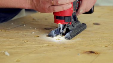 Yapboz elektrikli alet kullanan kişi. İşçi yapbozu iki eliyle tutuyor ve tahtadaki işaretli çizgiler boyunca ona rehberlik ediyor. - Evet. Yüksek kalite 4k görüntü