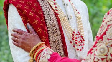 Geleneksel kırmızı ve beyaz Hint kıyafetleri içinde, Hindu düğün unsurları ile birbirlerine sarılmış düğün çifti. Kapatın. Yüksek kalite 4k görüntü