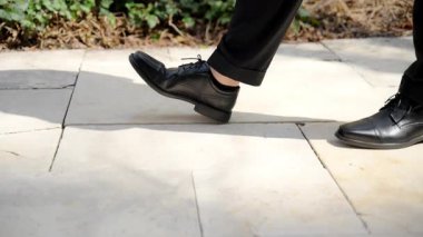 Siyah pantolonlu ve ayakkabılı bir adam sokakta yürüyor. Yüksek kalite 4k görüntü