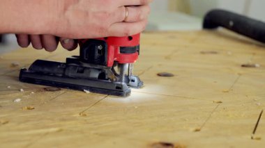 Yapboz elektrikli alet kullanan kişi. İşçi, yapbozu iki eliyle tutuyor ve tahtadaki işaretli çizgiler boyunca ona rehberlik ediyor. - Evet. Yüksek kalite 4k görüntü