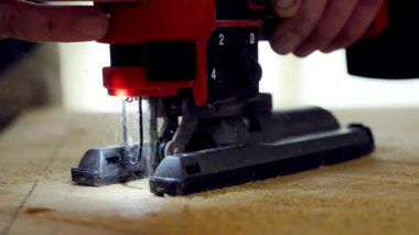 Yapboz elektrikli aletini kullanan kişi. İşçi iki eliyle yapboz tutuyor, tahta bir tahtanın üzerinde işaretli çizgiler boyunca ona rehberlik ediyor. - Evet. Yüksek kalite 4k görüntü