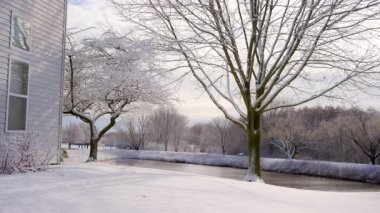 Güneşli bir kış gününde, donmuş göl ve evin yakınındaki ağaçlar karla kaplıydı. Yakın çekim görüntüsü. Yüksek kalite 4k görüntü