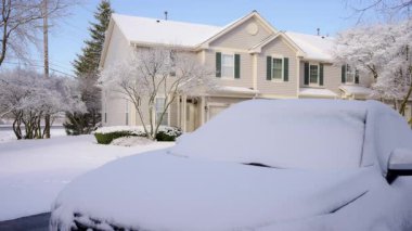 Parlak kış gününde, kar altında park etmiş arabaların olduğu bir evin fotoğrafını çekiyoruz. Yüksek kalite 4k görüntü