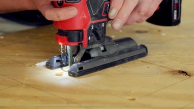 Yapboz elektrikli alet kullanan biri. İşçi, yapbozu iki eliyle tutuyor ve tahtadaki işaretli çizgiler boyunca ona rehberlik ediyor. - Evet. Yüksek kalite 4k görüntü