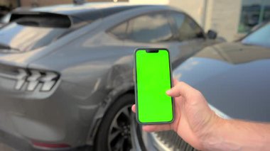 Kamera yeşil ekranlı akıllı telefona odaklan. Chroma anahtarı caddede iki arabanın olduğu bir araba kazası sahnesinde. Adam 911 'i arıyor. Hasarlı elementlerin görüntüsü. Stabil atış. Yüksek kalite 4k görüntü