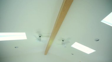 Tavan vantilatörü ve çatı pencereleri. Modern iç mekanda güneş gören pencereleri olan doğal ışık. Kamera hareketi. Yüksek kalite 4k görüntü