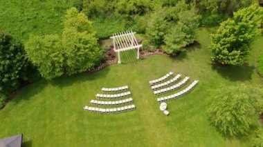 Açık hava beyaz ahşap kemerinin yukarıdan aşağı hava görüntüsü. Ortam ağaçlarla çevrili, çimenli bir alanda. Yüksek kalite 4k görüntü