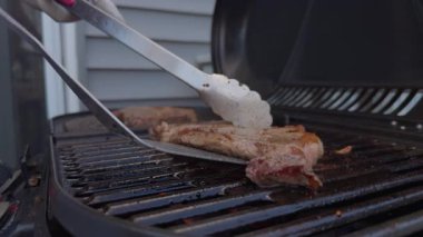 Et biftekleri ızgara yapıyor ve evin yakınındaki barbekü ızgarasını çeviriyor. Parti yemekleri. Yukarıdan aşağıya doğru. Yüksek kalite 4k görüntü