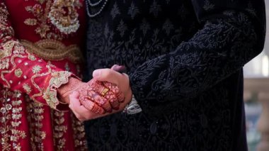 Damat, geleneksel kınalı gelinlerin el ele tutuşup fotoğraf için poz veriyor. Kırmızı renk geleneksel Hint kıyafetleridir, Hint düğününün unsurları. - Evet. Yüksek kalite 4k görüntü
