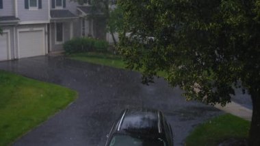 Şiddetli yağmur. Park yerindeki siyah arabanın üzerine yağmur damlaları düşer. Yağmurlu bir gün. Yukarıdan bak. Yüksek kalite 4k görüntü