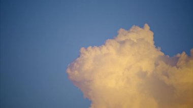 Arka planda mavi gökyüzü olan beyaz, tüylü, parlak bir bulut. Görüntüyü yakınlaştır. Yüksek kalite 4k görüntü