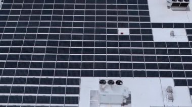 Yeşil ekolojik elektrik üretmek için ticari alışveriş merkezinin çatısına monte edilmiş güneş enerjisi panellerinin havadan yakın görüntüsü. Yüksek kalite 4k görüntü