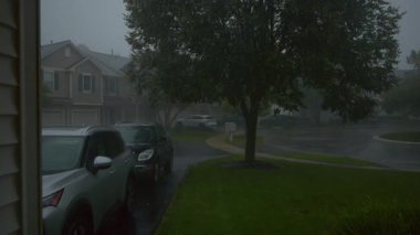 Şiddetli yağmur, yerleşim alanındaki sakin bir banliyö sokağına yağar. Şiddetli rüzgar ve şimşek korkunç bir atmosfer yaratır. Evin manzarası. Yüksek kalite 4k görüntü
