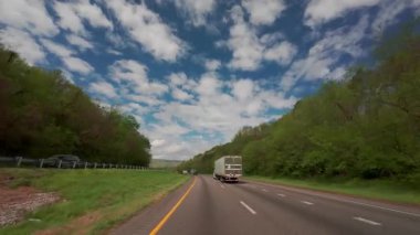 Yeşil yay yapraklı, parlak mavi bir gökyüzünün altında otoyolda giden teslimat kamyonunun görüntüsü. Lojistik ve ulaşım konsepti. Atlanta GE. ABD 2 Mayıs 2025. Yüksek kalite 4k görüntü