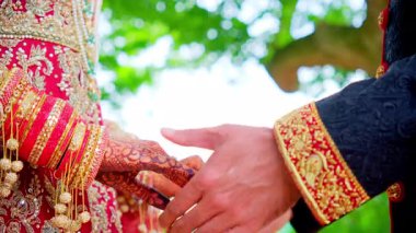 Gelin ve damat el ele tutuşuyor. Geleneksel kınalı gelin eli. Hint nakışlı giysilerinde kırmızı ve siyah renkler, Asya düğün unsurları. - Evet. Yüksek kalite 4k görüntü