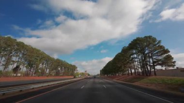 Boş otobanda, parlak mavi bir gökyüzünün altında, tüylü beyaz bulutların altında giden arabadan POV görüntüsü. ABD TN Chattanooga 01 Nisan 2025. Yüksek kalite 4k görüntü