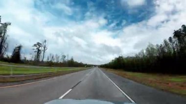 Otoyolda ağır beyaz bulutların altında araba sürmek. Ön yolcu koltuğundan POV görüntüsü. Zaman ayarlı. Yüksek kalite 4k görüntü