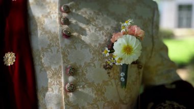 Groom Dressed in traditional Indian or Pakistan wedding beige suit with red color elements . Groom adjusting flower boutonniere. Close up footage. High quality 4k footage